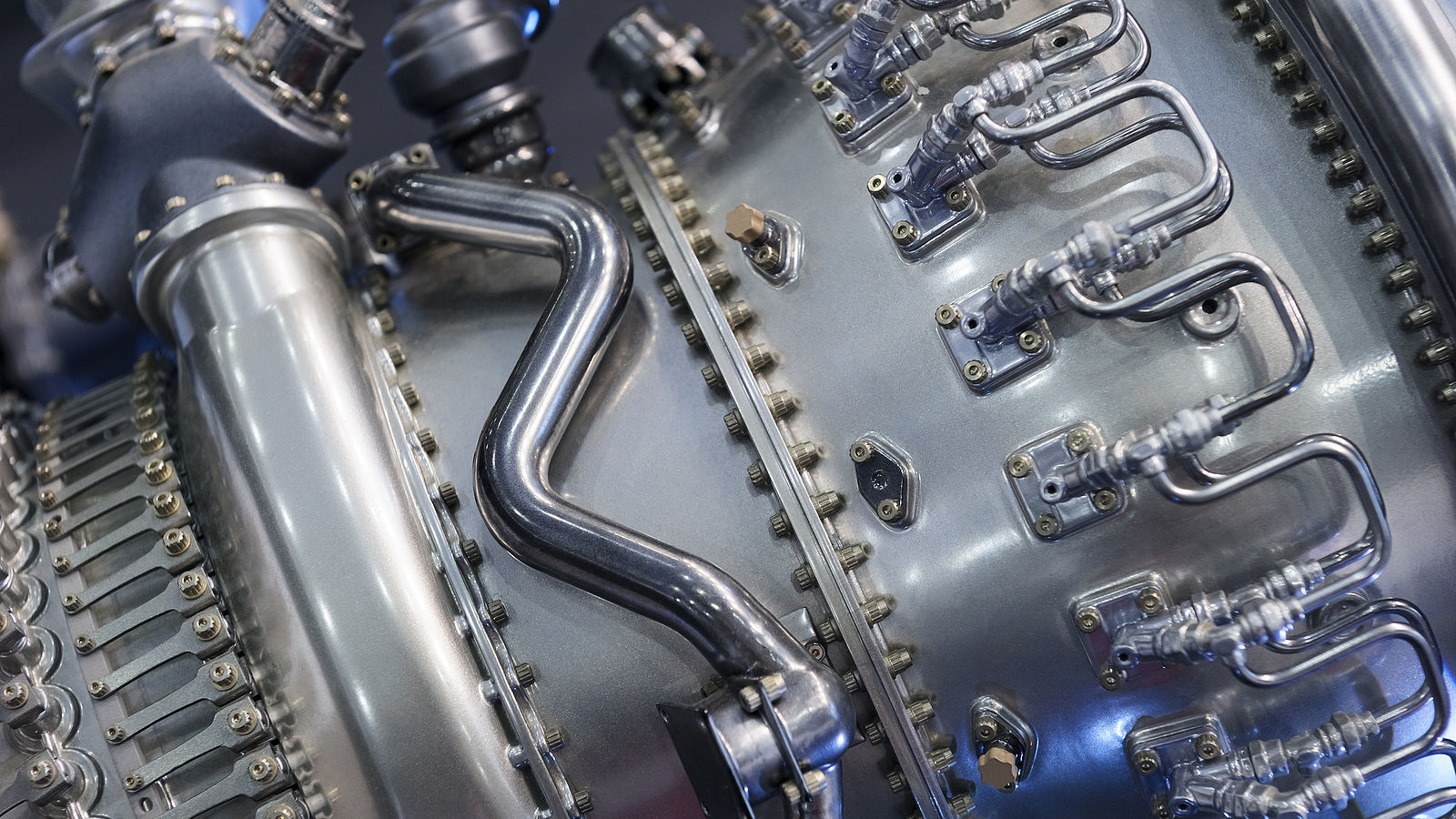 Close-up of a precision-engineered metallic component with tubing and fasteners, commonly used in military or aerospace equipment.